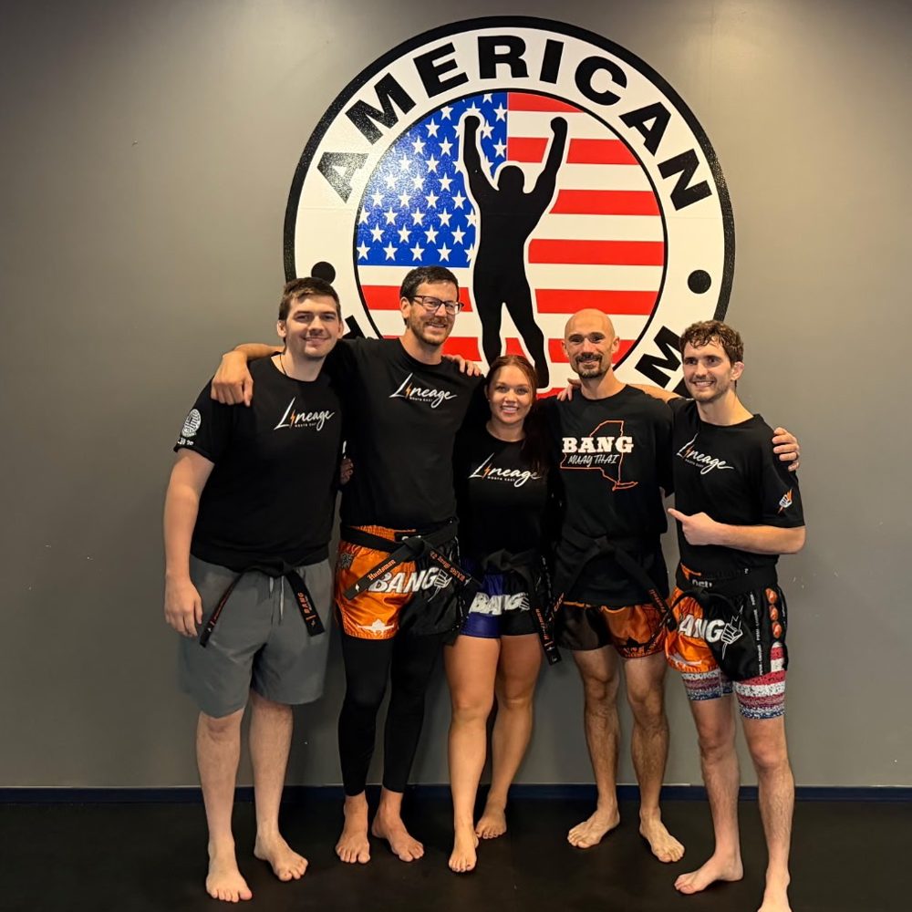 The five BANG Muay Thai black belt coaches at ATT Watertown in front of the American Top Team logo