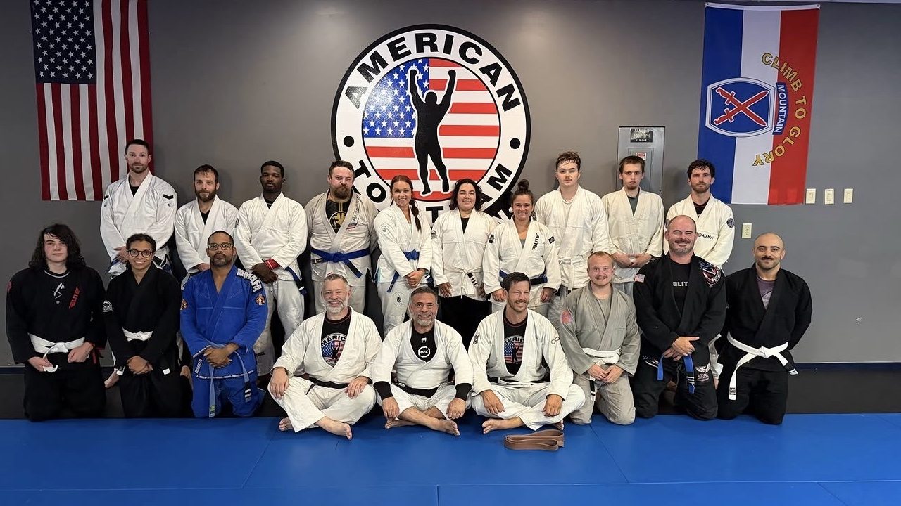 Brazilian Jiu Jitsu gi class group photo at ATT Watertown, with US flag and 10th Mountain Division flag on the wall